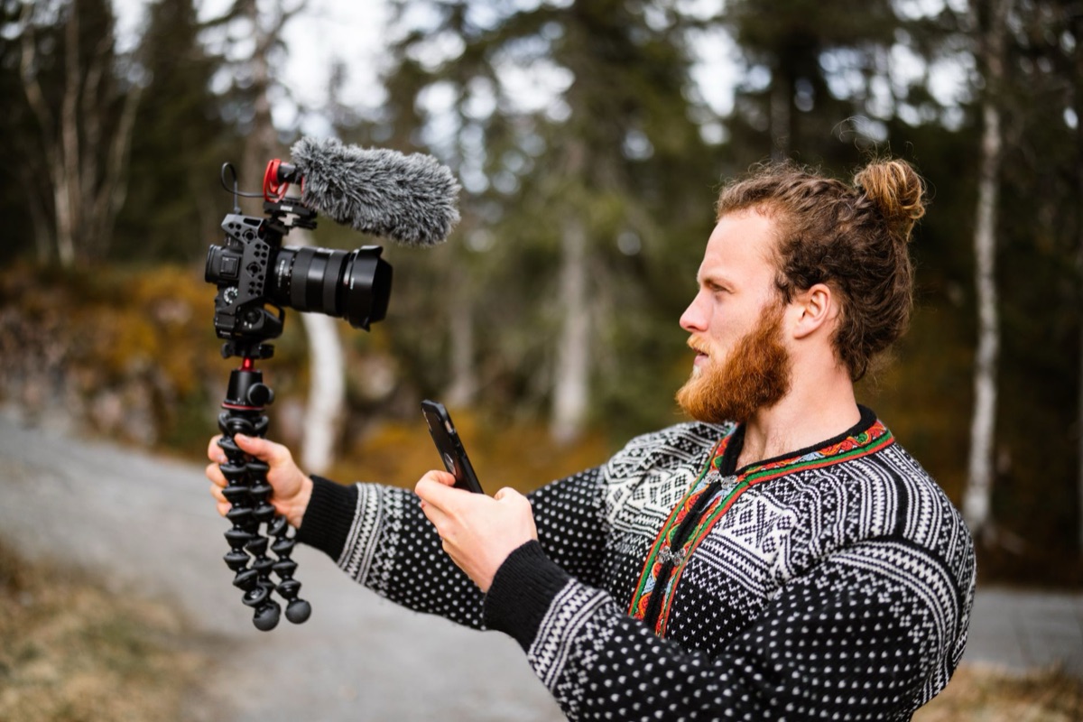 Une personne utilisant un camécopeur compact avec un microphone externe pour le vlogging.