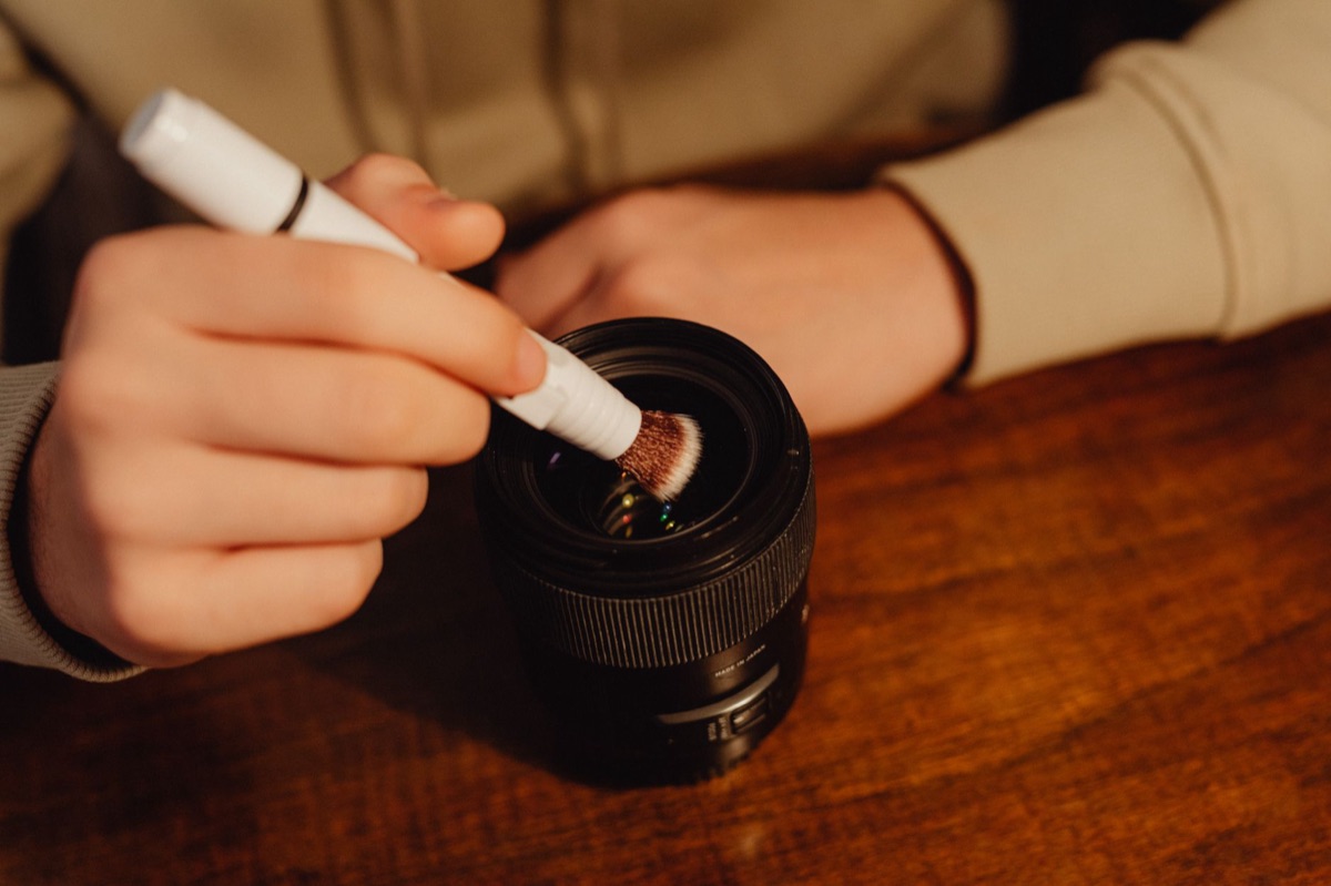 A specialized lens cleaning brush and microfiber cloth for camera maintenance.