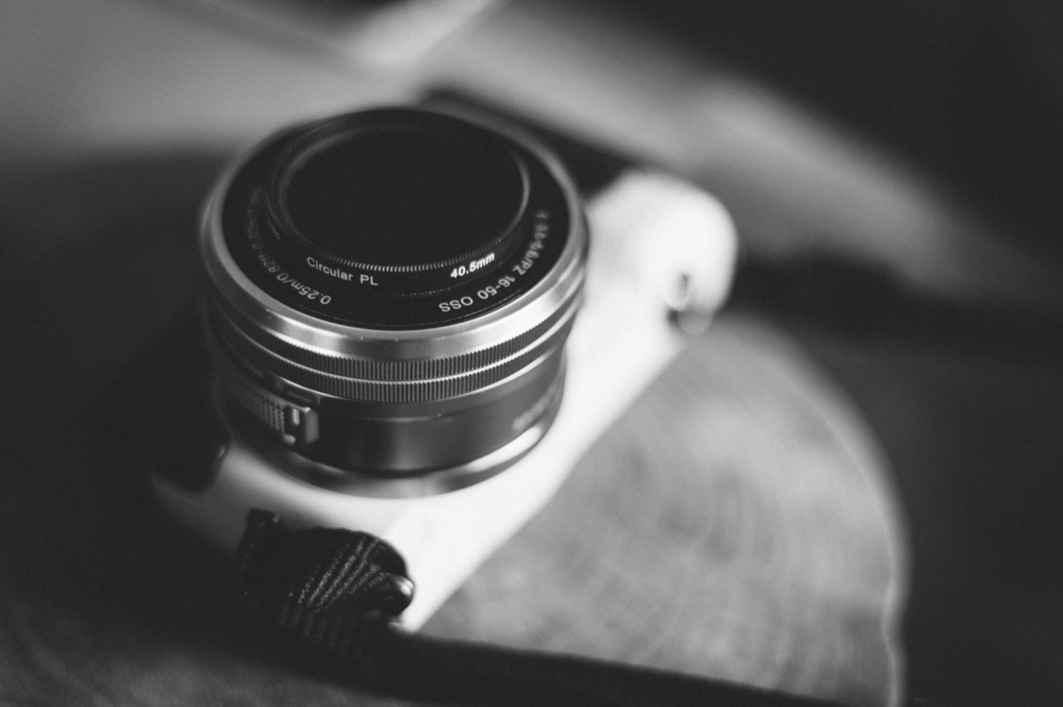 Mano de un fotógrafo enroscando un filtro protector en el objetivo de una cámara.