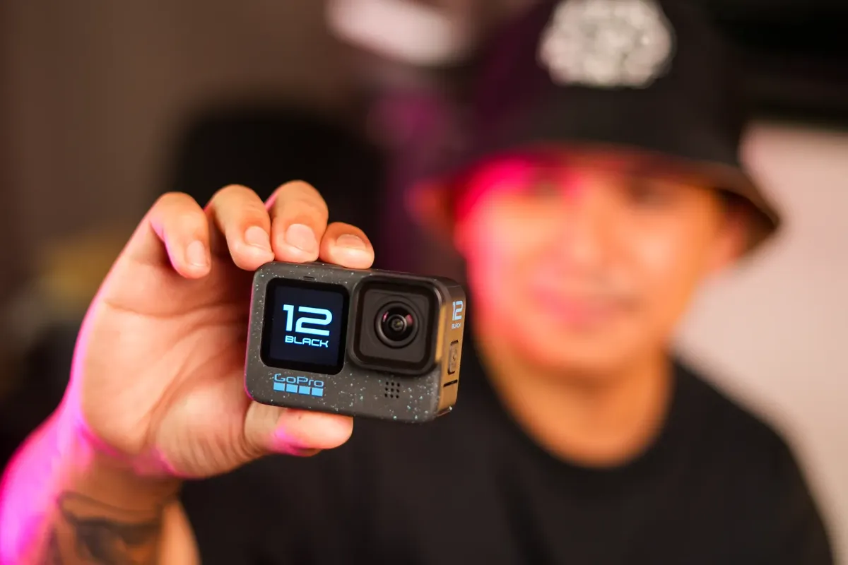 A close-up image of a man holding an action camera in his hand, showcasing its design.