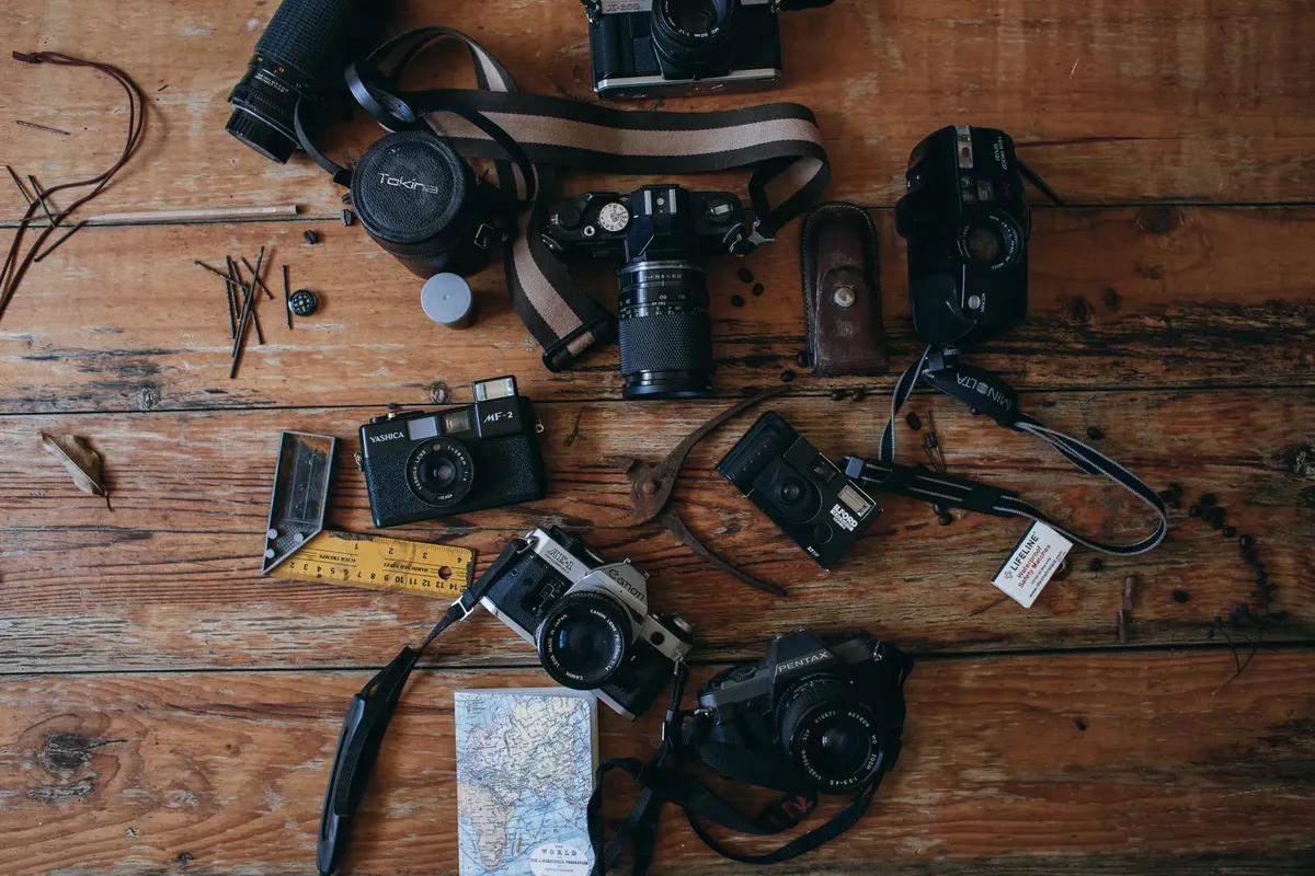 Top view of various vintage photo camera on straps placed on wooden background with map near joiners square in room